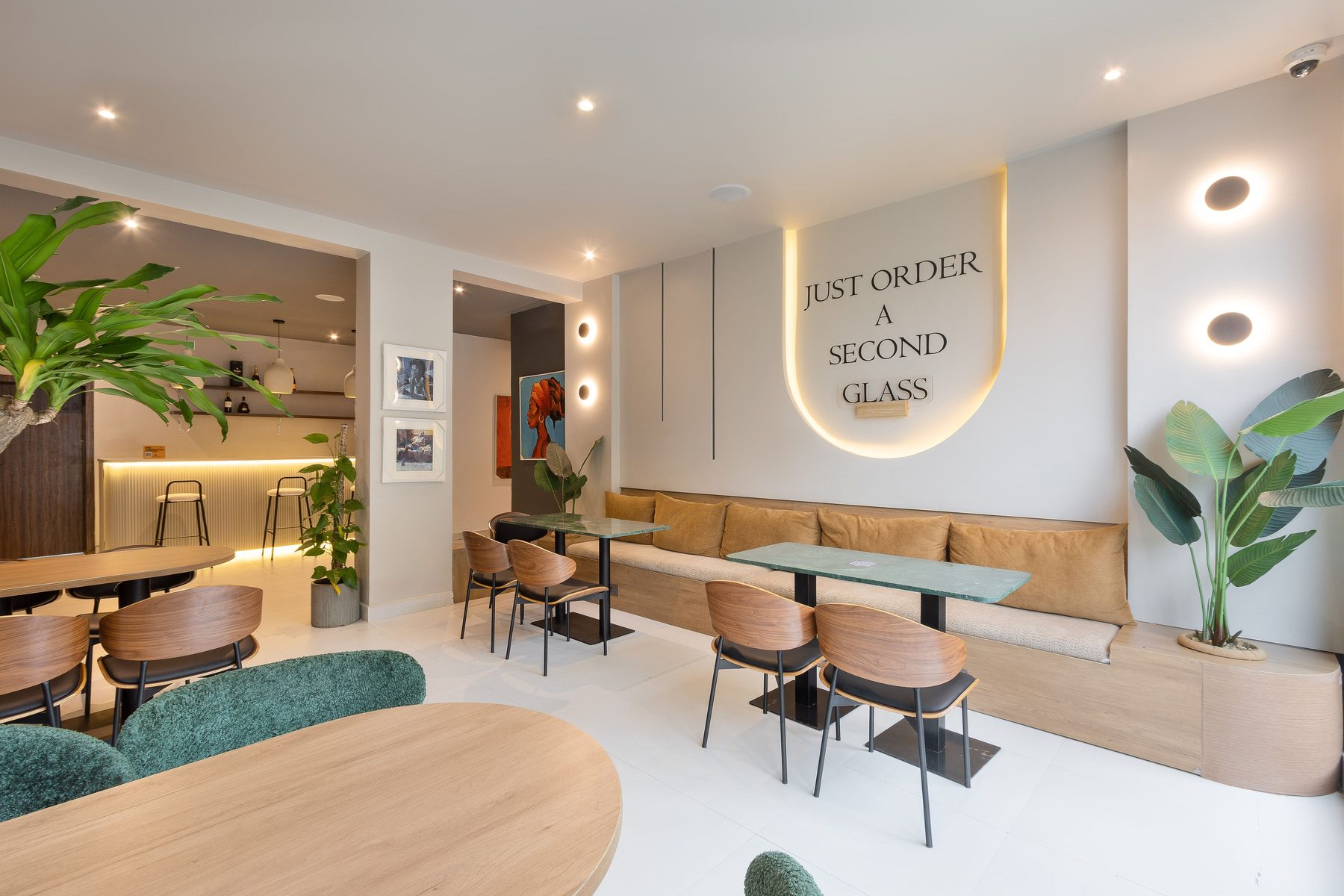 The dining room at R&M Lagos with green marble tables and banquette seating